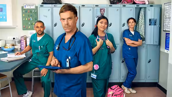 Dylan Keogh (William Beck) holds a tablet among colleagues in the hospital changing room