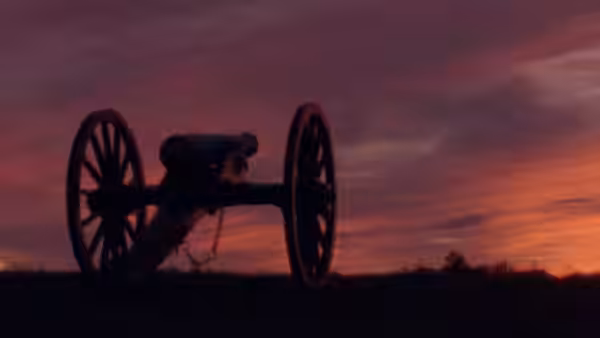 A cannon stands silhouetted against a red sunset