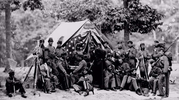Union soldiers gather around a tent decorated with a star-spangled banner