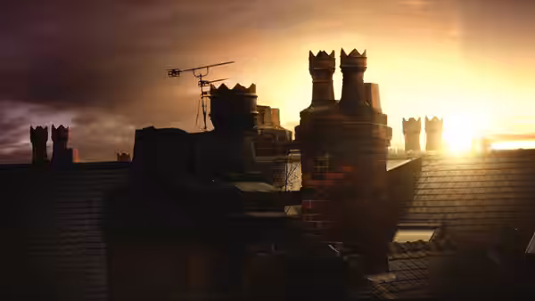 Brick chimneys and rooftops silhouette against the setting sun
