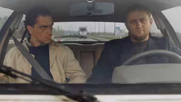 Rex Hofman (Gene Bervoets) rides beside Raymond Lemorne (Bernard-Pierre Donnadieu) on a highway
