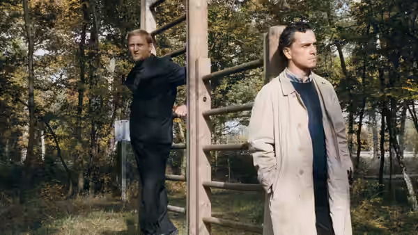 Rex Hofman (Gene Bervoets) stands beside Raymond Lemorne (Bernard-Pierre Donnadieu) at a wooden climbing frame
