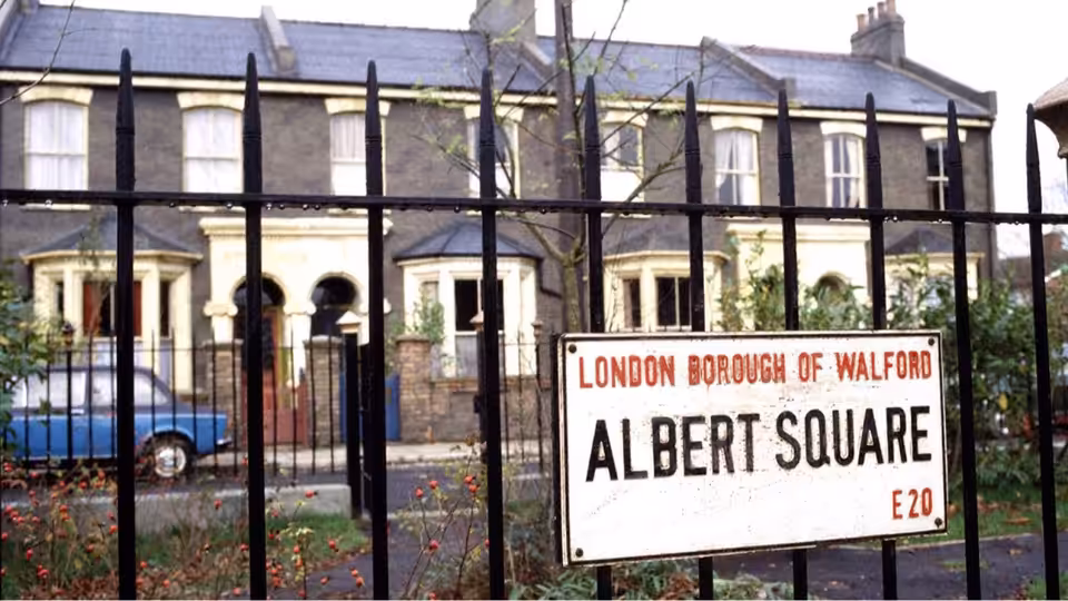 An Albert Square sign stands before a row of houses behind iron railings