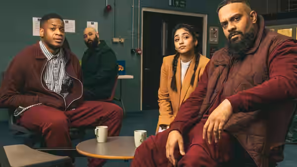 Four people sit around a small table in a green-walled waiting room