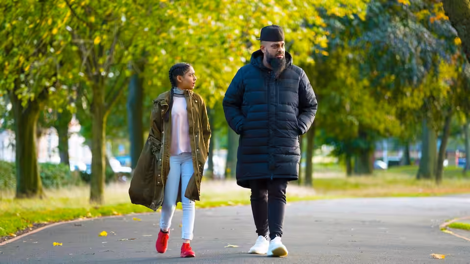 Mobeen (Guz Khan) walks beside Aqsa (Duaa Karim) along a tree-lined park path