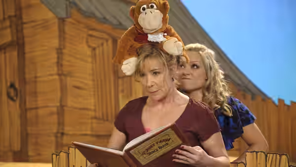 Susan Harper (Zoë Wanamaker) reads a storybook with a monkey puppet on her head