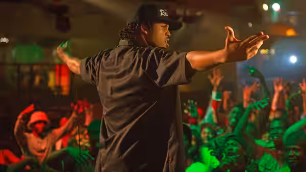 performer on stage with arms outstretched facing an excited crowd