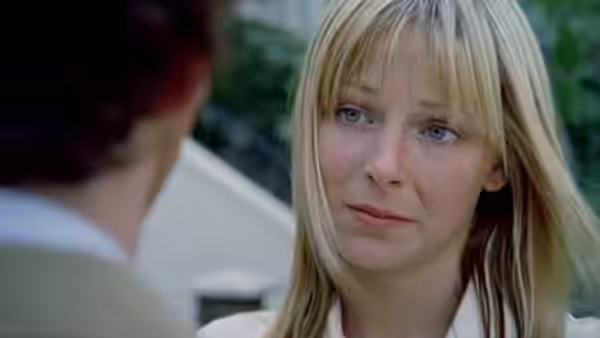 A blonde woman listens to someone outdoors