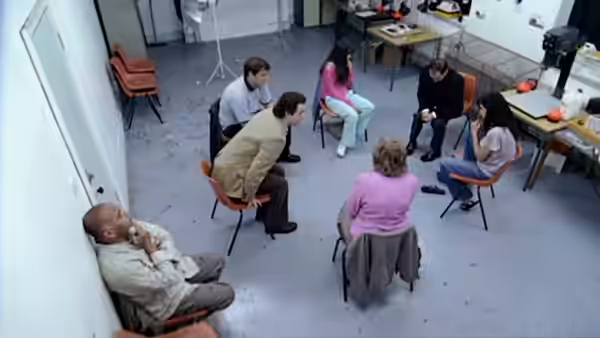 People sit in a circle of chairs during a group meeting