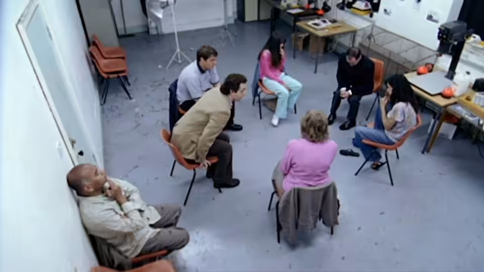 People sit in a circle of chairs during a group meeting