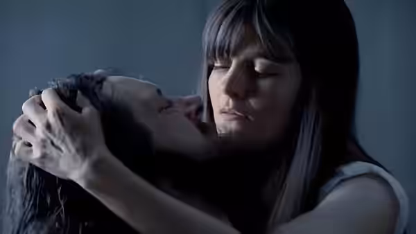 A dark-haired woman holds a man's head gently in her hands