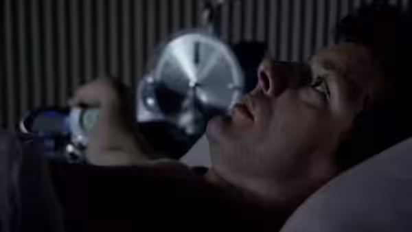 Mark Furness (Michael Sheen) lies in bed, gazing toward a fan
