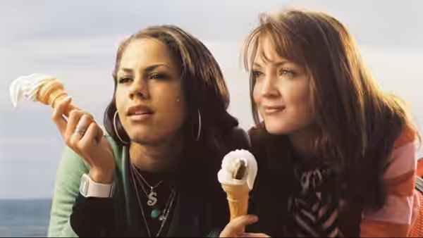 Two women hold ice cream cones by the seaside