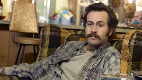 Earl Hickey (Jason Lee) reclines in a plaid armchair inside a cluttered trailer