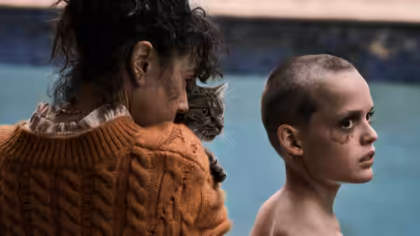 A woman holds a cat beside a boy by a tiled pool