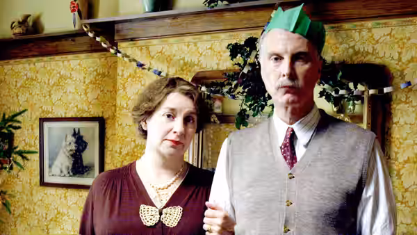 Nella Last (Victoria Wood) stands beside Will Last (David Threlfall) in party hats at home