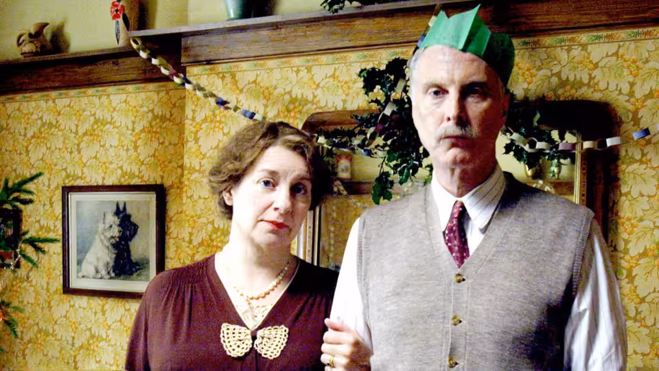 Nella Last (Victoria Wood) stands beside Will Last (David Threlfall) in party hats at home