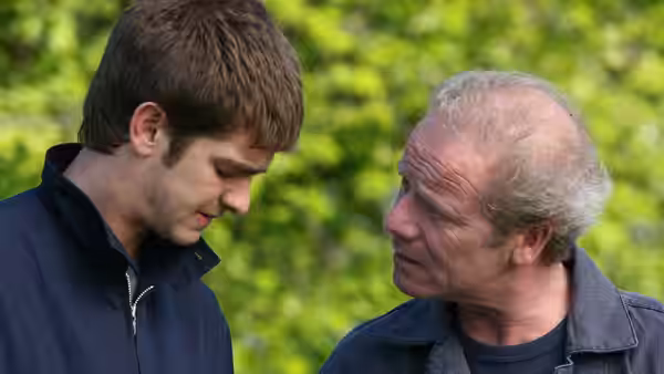 Jack (Andrew Garfield) listens to an older man in a leafy outdoor setting