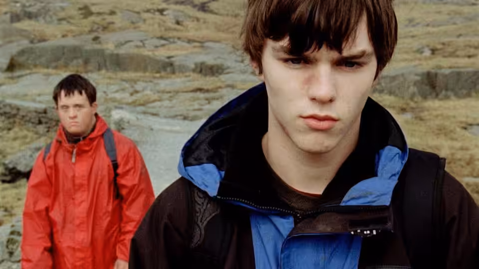 David Philips (Nicholas Hoult) stands before Ben Philips (Tommy Jessop) on rocky terrain