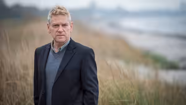 Kurt Wallander (Kenneth Branagh) stands among dune grass overlooking the coast