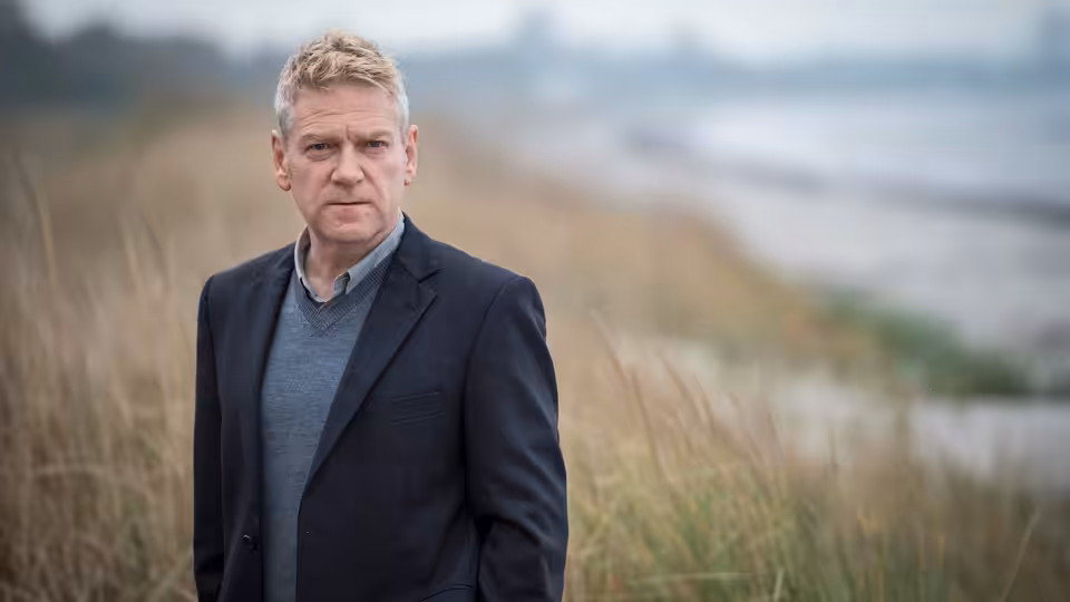 Kurt Wallander (Kenneth Branagh) stands among dune grass overlooking the coast