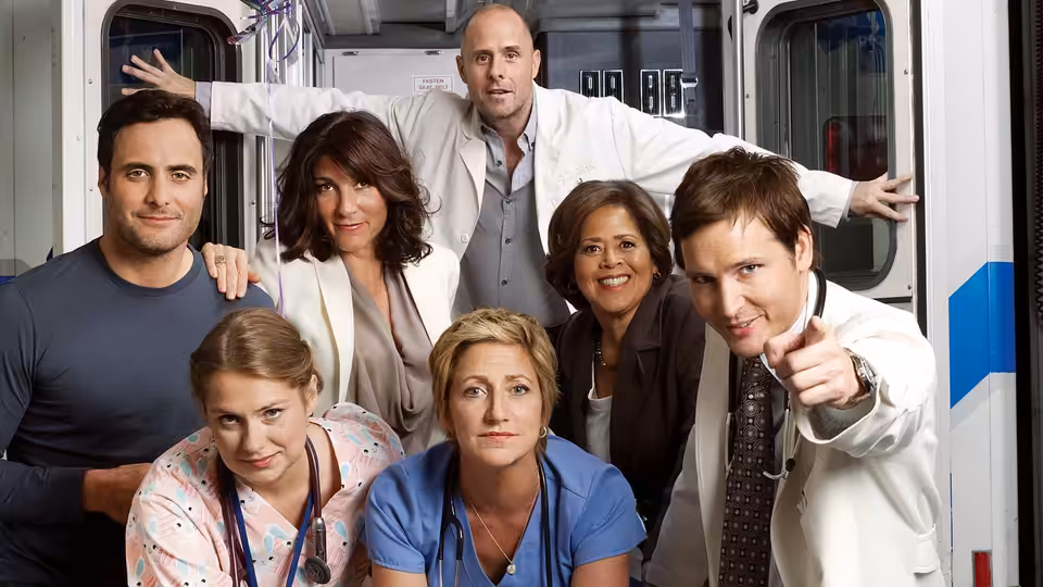 Hospital staff gather in a corridor as a doctor in a white coat points outward