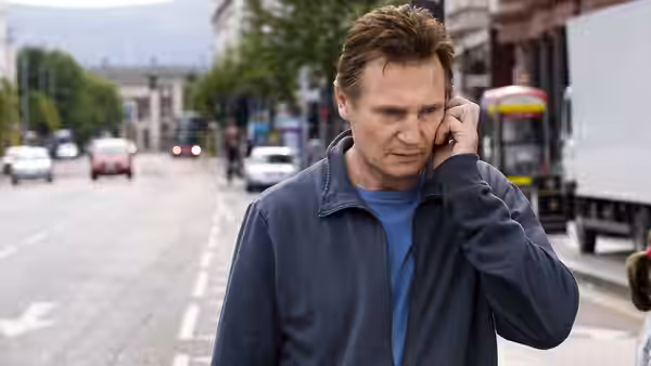 Alistair Little (Liam Neeson) talks on a phone on a city street