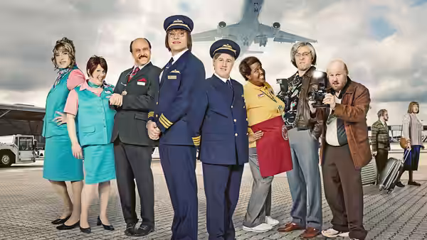 Airport staff and travelers pose on the tarmac beneath a passenger plane