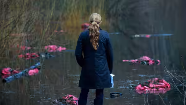 Sarah Linden (Mireille Enos) surveys bright pink garments floating in a flooded woodland
