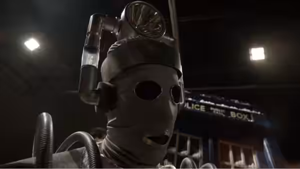 A masked mechanical figure stands before a blue police box beneath studio lights