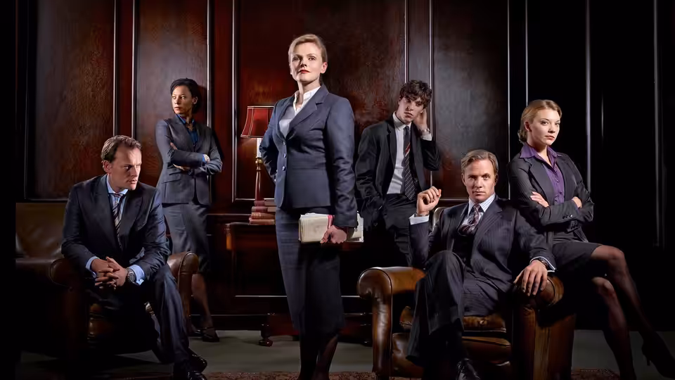 Martha Costello (Maxine Peake) stands among barristers in a wood-panelled legal chamber
