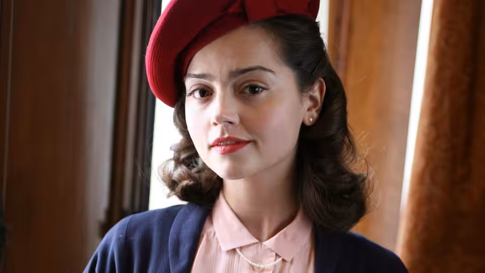 Susan Brown (Jenna Coleman) wearing a red hat beside a curtained window
