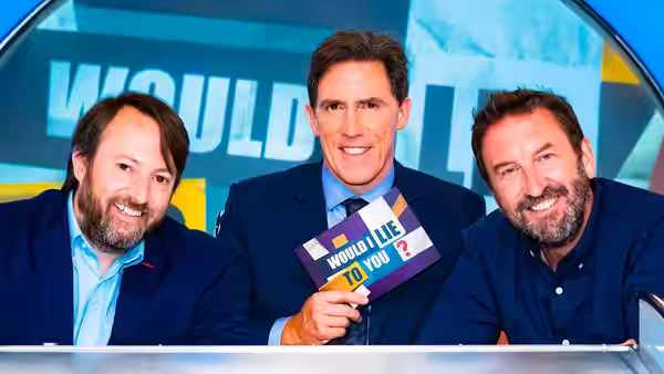 David Mitchell and Lee Mack flank Rob Brydon, who holds a show card