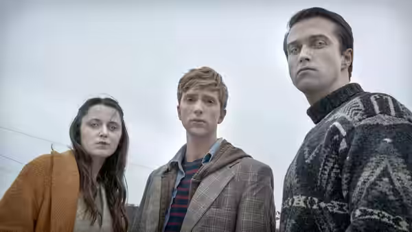 Kieren Walker (Luke Newberry) stands outdoors with a young woman and a man