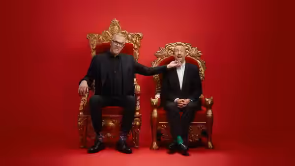 Greg Davies touches Alex Horne’s chin while they sit on ornate thrones