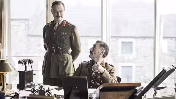 General Mitford (Michael Palin) sits at his desk as another officer stands beside him