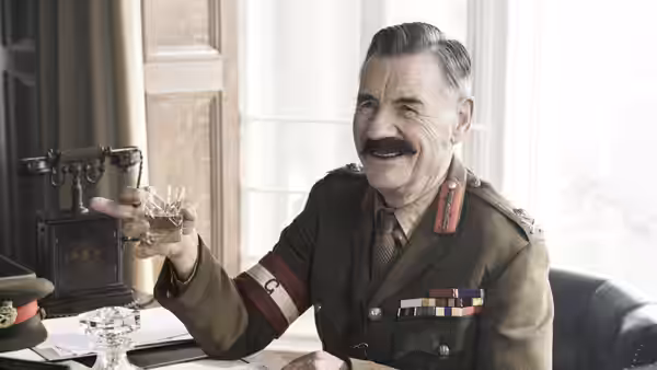 General Mitford (Michael Palin) raises a glass in his office