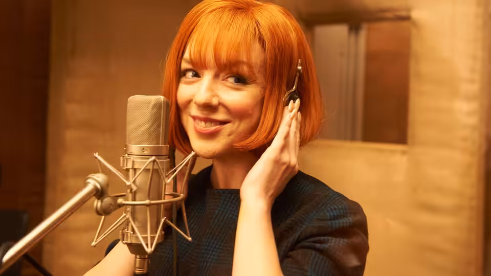 Cilla Black (Sheridan Smith) wearing headphones at a recording studio microphone