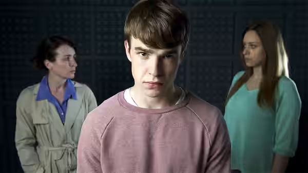 Johnjo O'Shea (Nico Mirallegro) faces forward as two women stand behind him