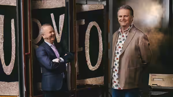 Ian Hislop and Paul Merton stand beside oversized lettering, smiling at the camera