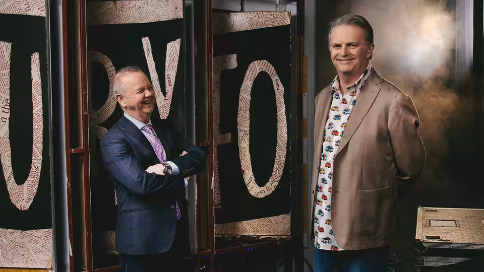Ian Hislop and Paul Merton stand beside oversized lettering, smiling at the camera