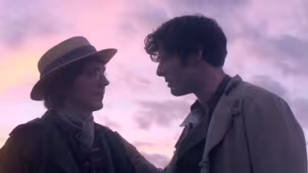 A man in a brimmed hat faces a younger man on a hillside at dusk