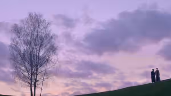 Two men stand together on a grassy ridge beneath a cloudy evening sky