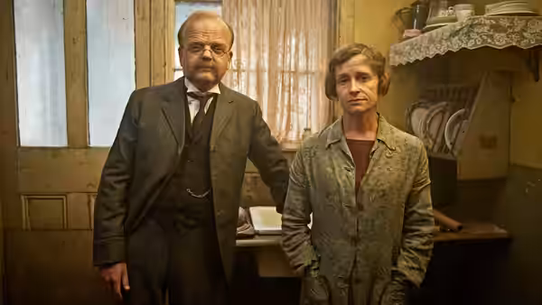 John Mayhew (Toby Jones) and Alice Mayhew (Hayley Carmichael) stand together in a cluttered room