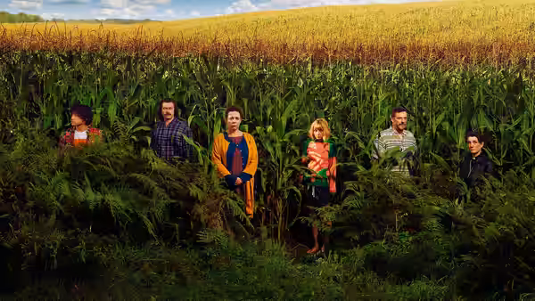 Six people stand among tall corn and ferns in a field