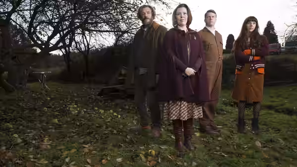 Deborah Flowers (Olivia Colman) and her family stand beneath a tree in the garden