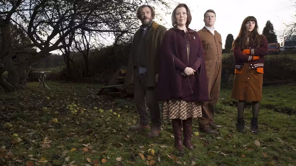 Deborah Flowers (Olivia Colman) and her family stand beneath a tree in the garden