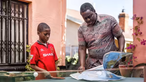 Richard Taylor (Babou Ceesay) and Damilola (Sammy Kamara) look over a map at a garden table