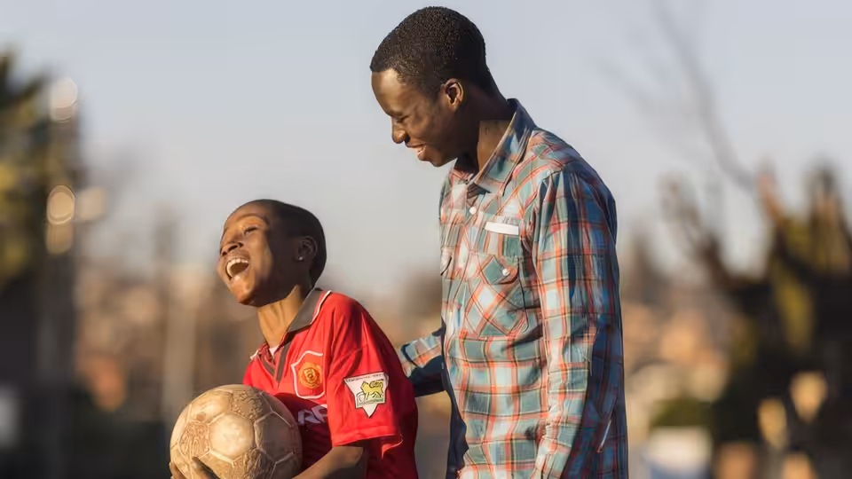 Damilola Taylor (Sammy Kamara) laughs with his father Richard (Babou Ceesay), holding a football
