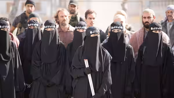 Women in black veils stand in a crowd as one holds a white cane